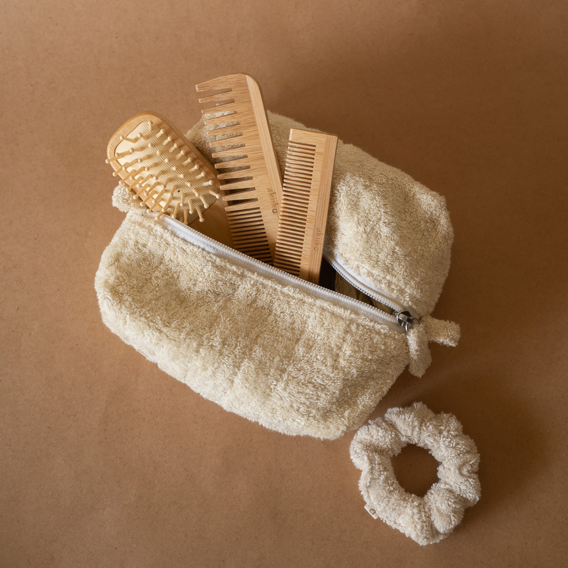 Bamboo Hair Set featuring a bamboo hair brush, pocket comb, regular comb, soft terry scrunchie, all stored in a terry pouch.