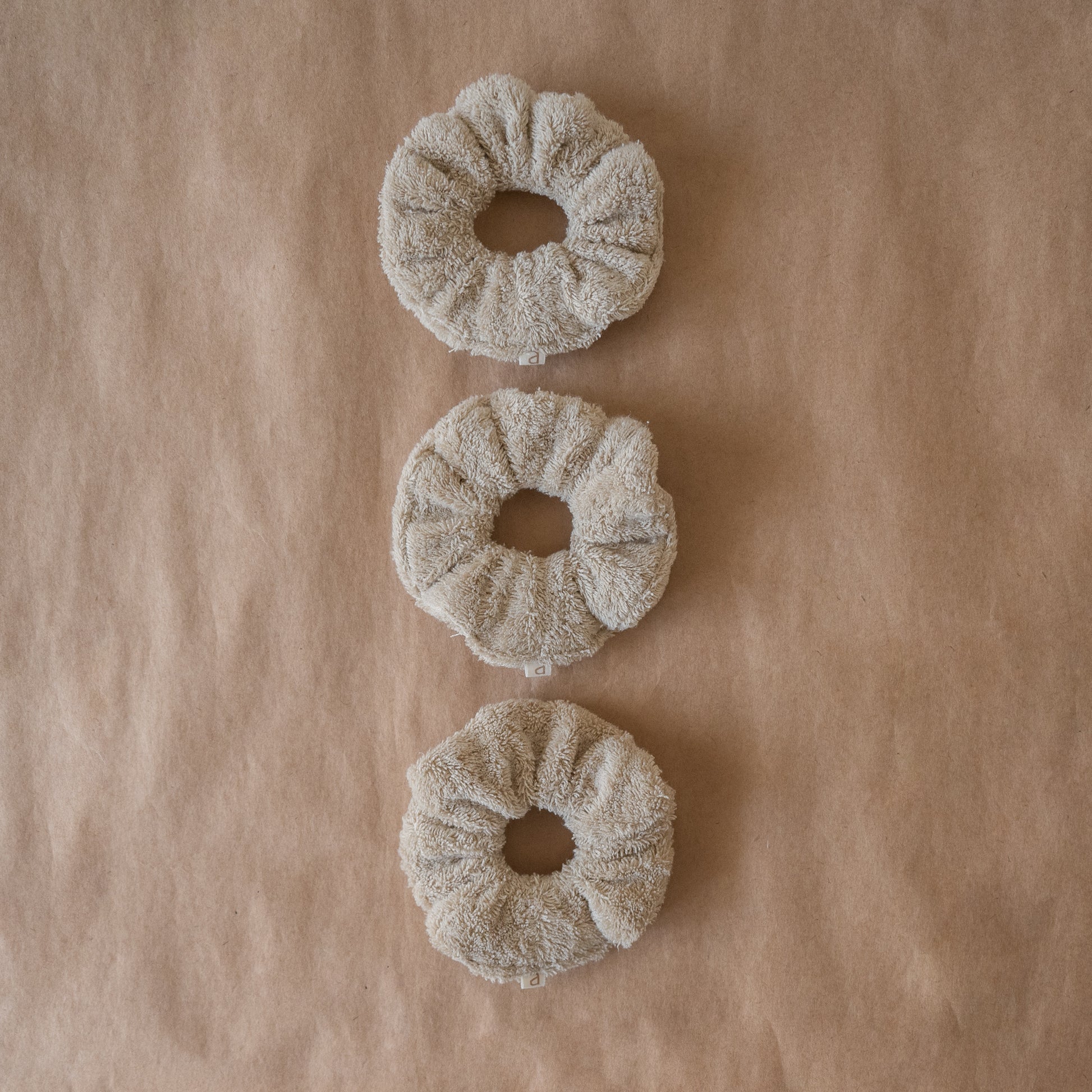 Set of three fluffy terry cotton cloud scrunchies in neutral tones, soft and lightweight, with pouch.