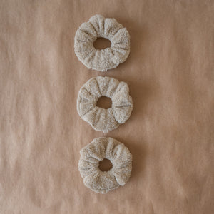Set of three fluffy terry cotton cloud scrunchies in neutral tones, soft and lightweight, with pouch.
