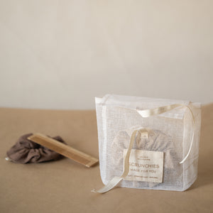 Pack of 3 crinkle cotton scrunchies in natural, wheat, and espresso tones, packaged in a mesh pouch.