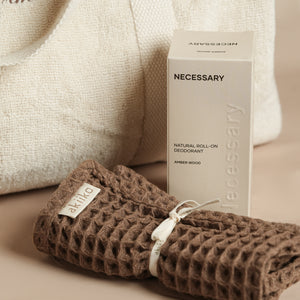 Fresh Companion Set featuring a soft terry cotton duffle with espresso embroidery and charm, matching espresso waffle face towel, and Necessary Amber Wood aluminum-free deodorant.
