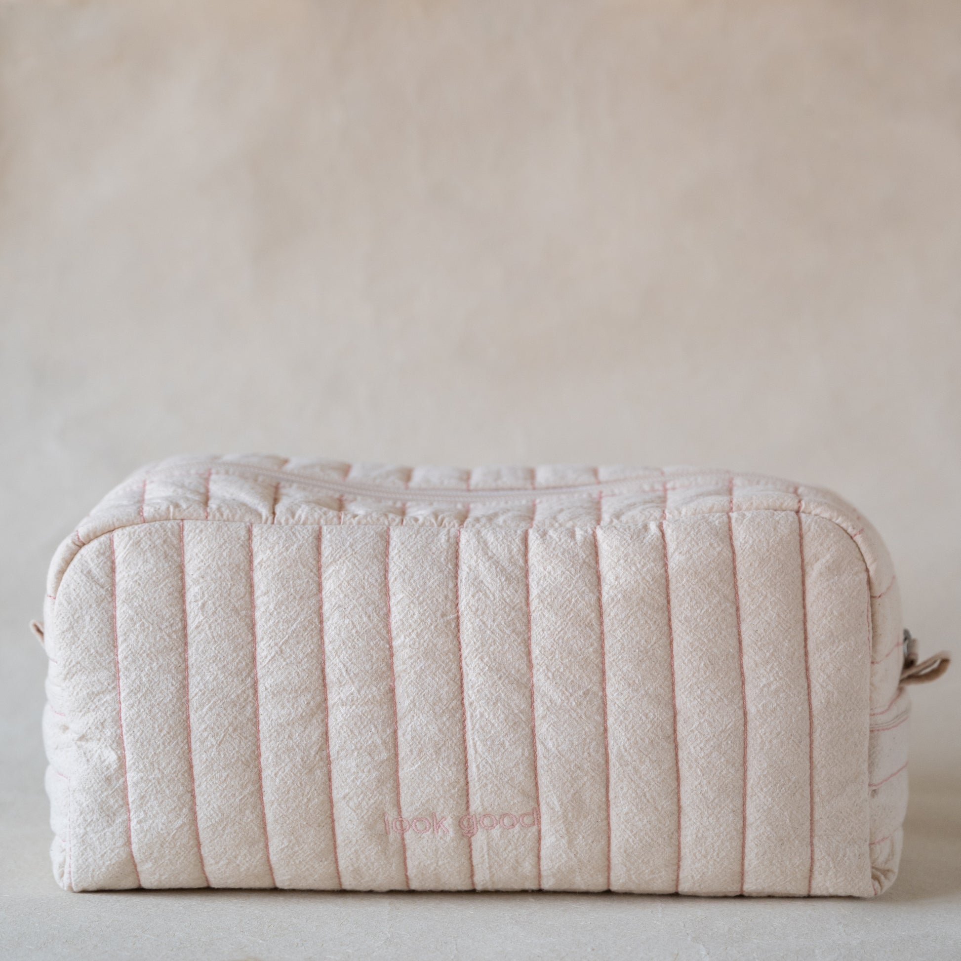 Long curved crinkle-cotton pouch with “look good” pink embroidery, front view