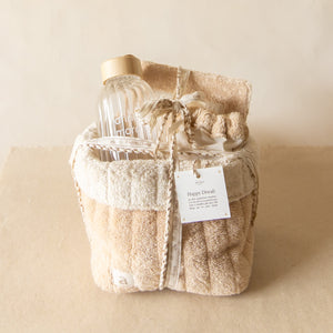 PM Cloud Self–Care Set featuring a foldover cloud terry basket with eyemask in drawstring pouch, terry sleep journal, and glass water bottle.