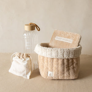 PM Cloud Self–Care Set featuring a foldover cloud terry basket with eyemask in drawstring pouch, terry sleep journal, and glass water bottle.