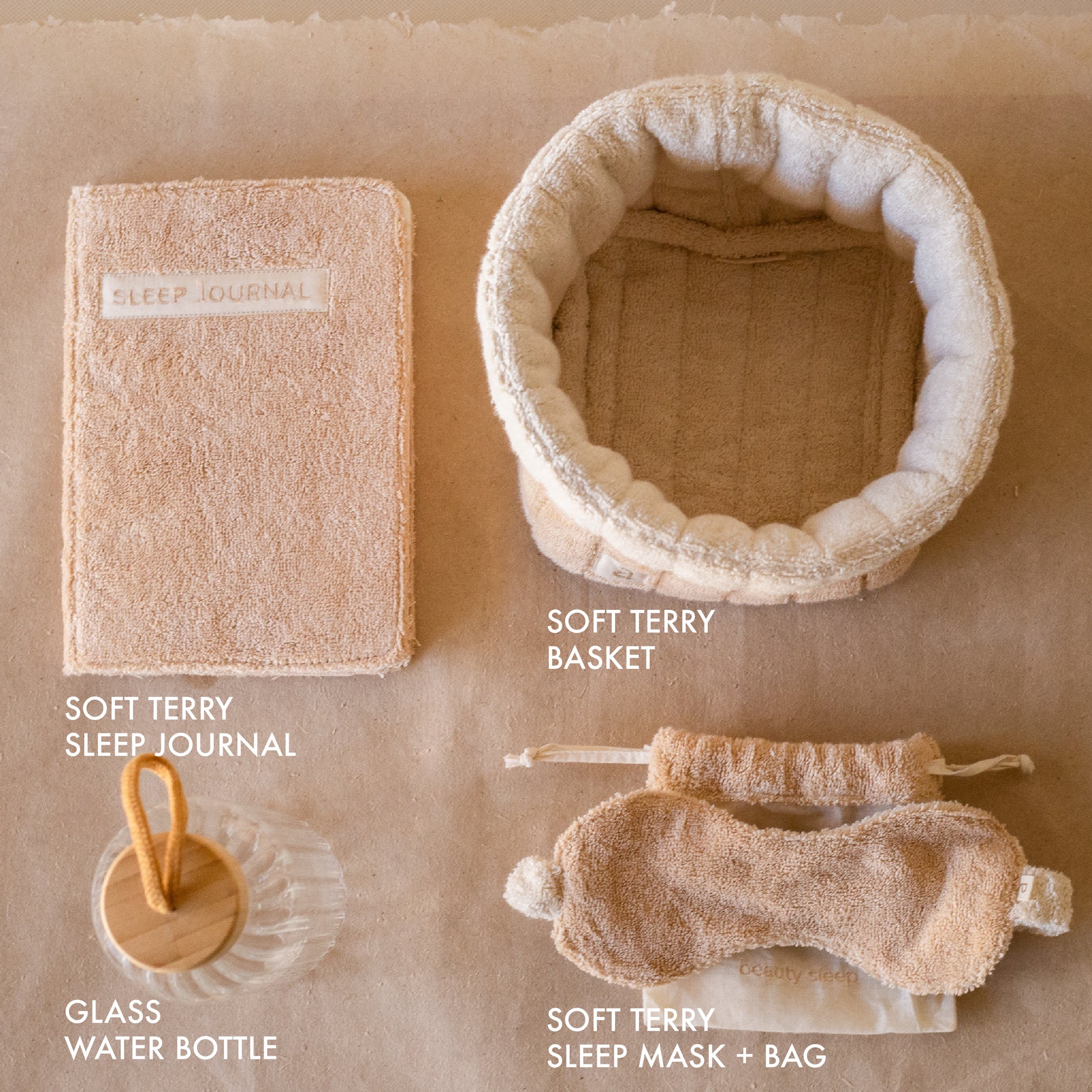 PM Cloud Self–Care Set featuring a foldover cloud terry basket with eyemask in drawstring pouch, terry sleep journal, and glass water bottle.