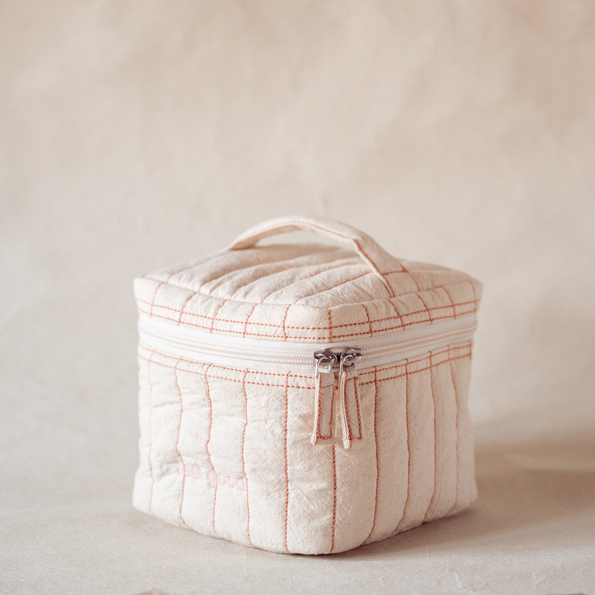 Pink-striped square vanity pouch with “feel good” embroidery, front view