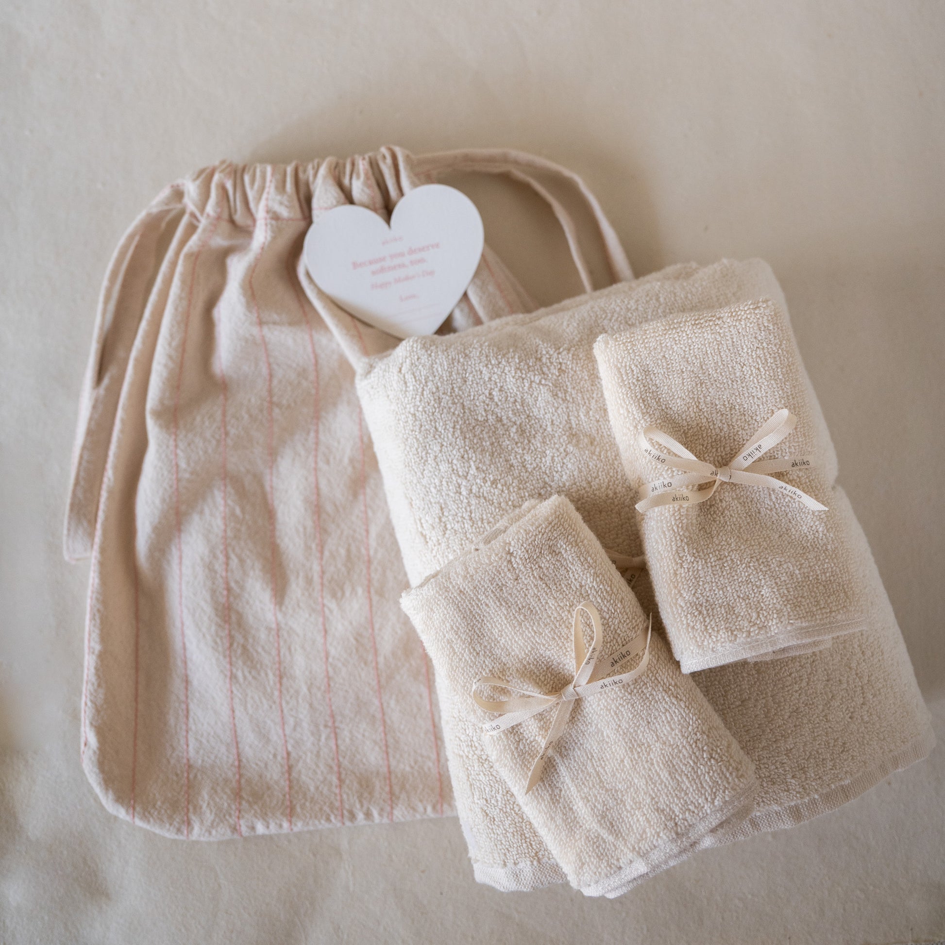 Rosette Soft Towel Gift Set featuring one plush soft terry bath towel, two matching hand towels, and a crinkled cotton drawstring bag with pink thread details.