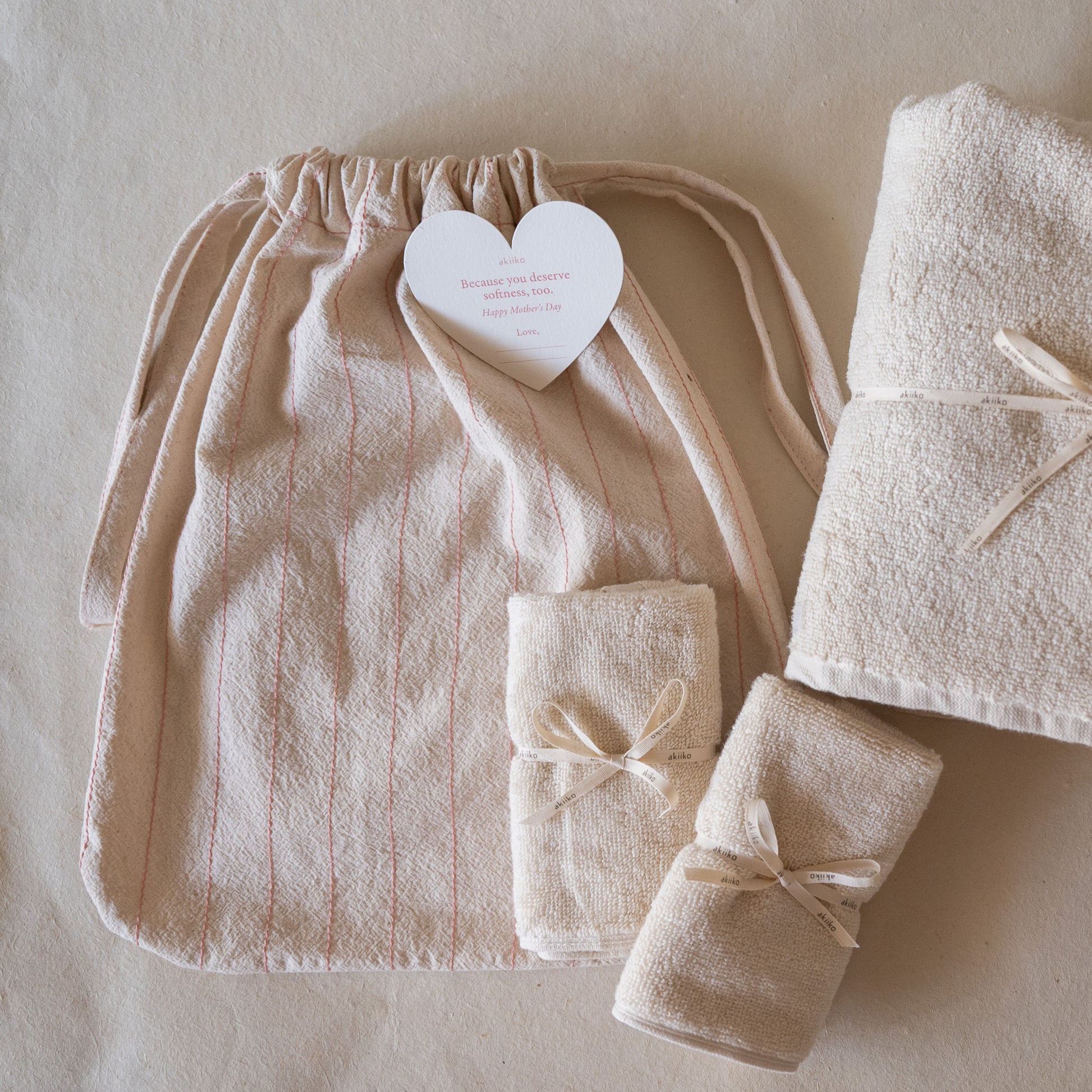 Rosette Soft Towel Gift Set featuring one plush soft terry bath towel, two matching hand towels, and a crinkled cotton drawstring bag with pink thread details.