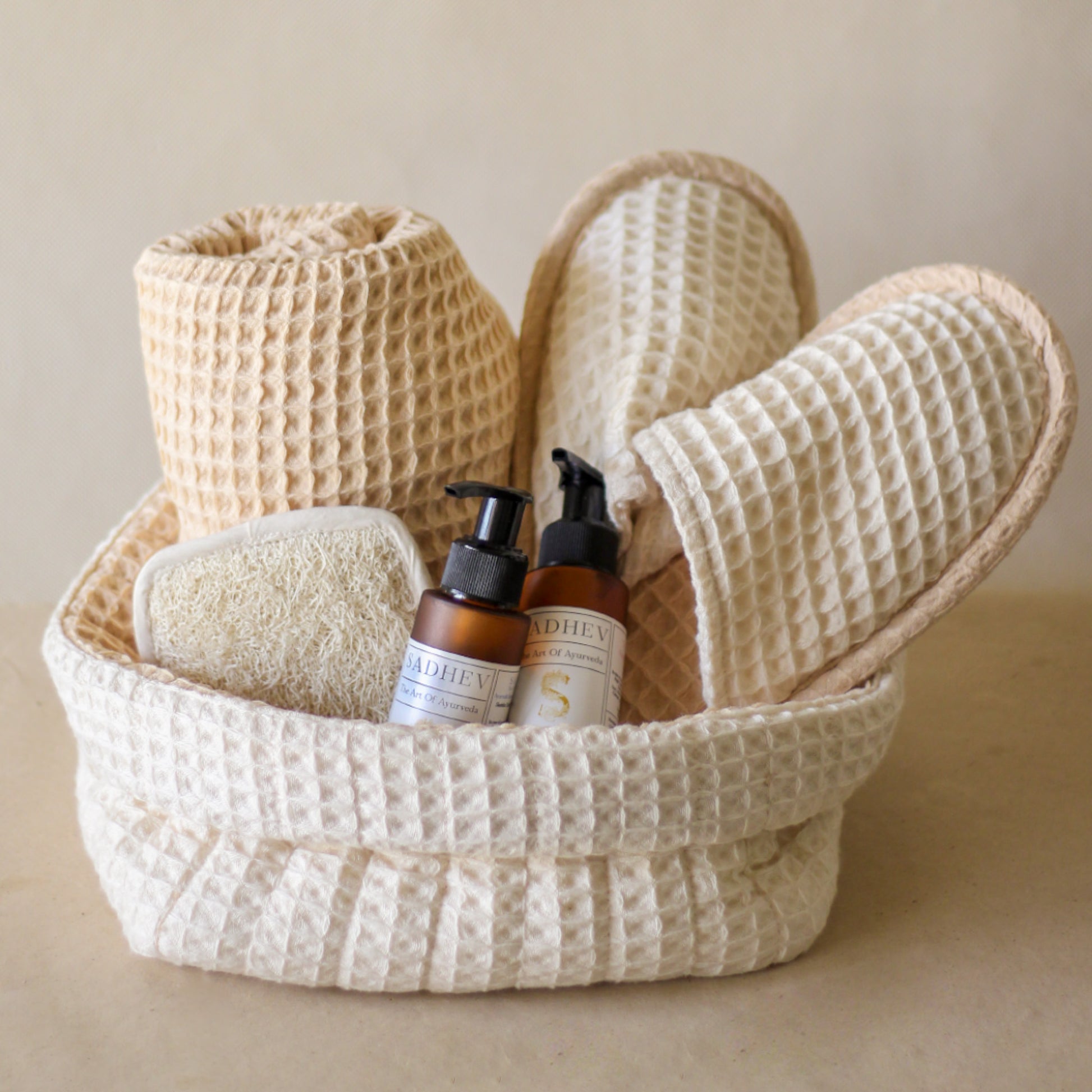 Soak & Soothe Bath Kit featuring Ayurvedic shower gel, body lotion, waffle luffa scrubber, latte waffle bath towel, cozy bath slippers, and a waffle storage basket.