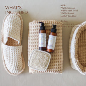 Soak & Soothe Bath Kit featuring Ayurvedic shower gel, body lotion, waffle luffa scrubber, latte waffle bath towel, cozy bath slippers, and a waffle storage basket.