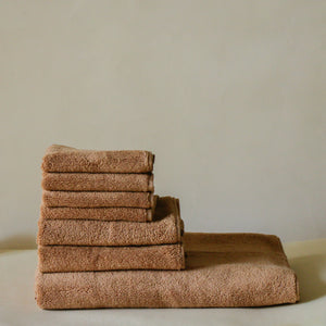Light-colored soft terry cotton towel set with bath, hand, and face towels, plush and highly absorbent.