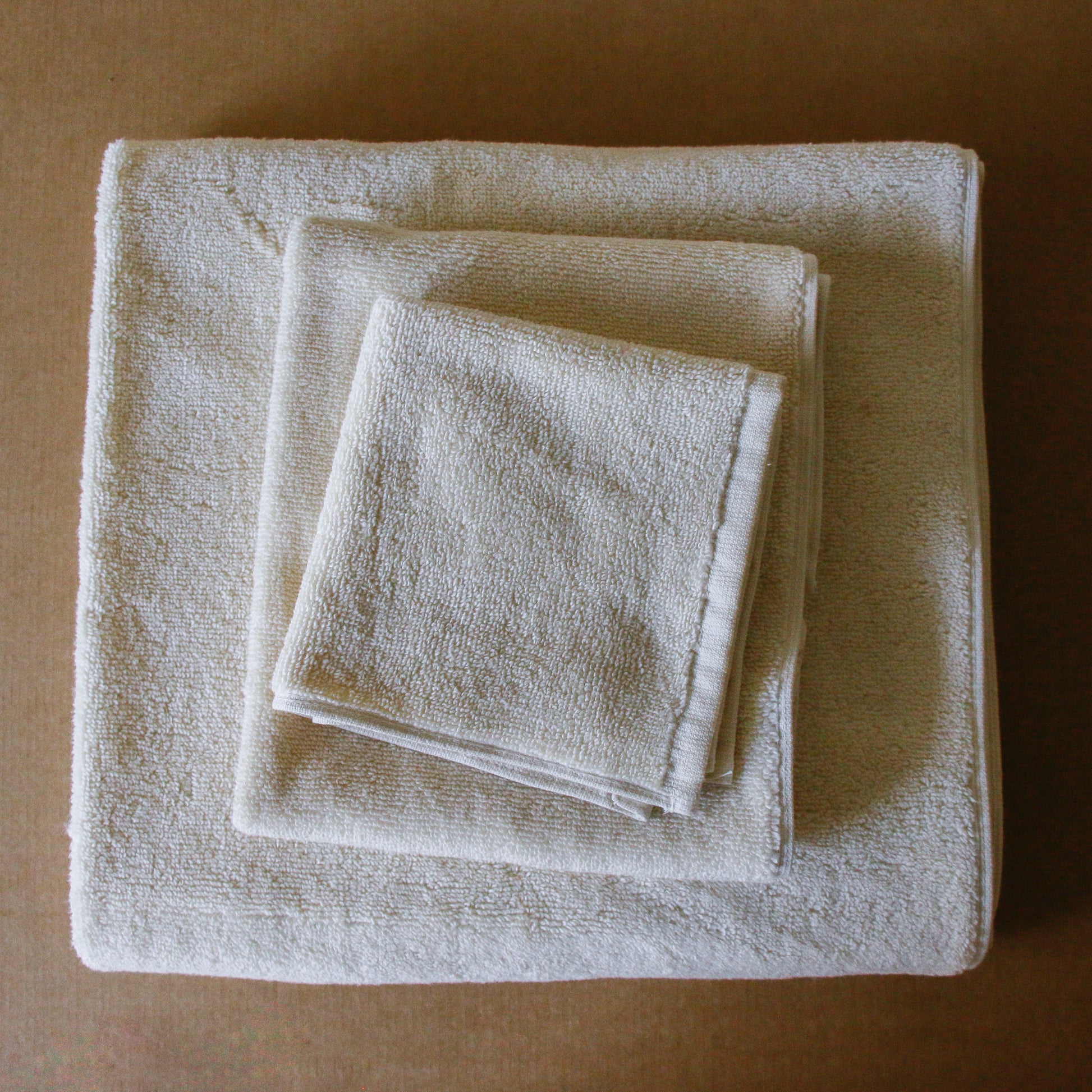 Light-colored soft terry cotton towel set with bath, hand, and face towels, plush and highly absorbent.