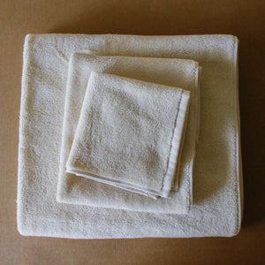 Light-colored soft terry cotton towel set with bath, hand, and face towels, plush and highly absorbent.