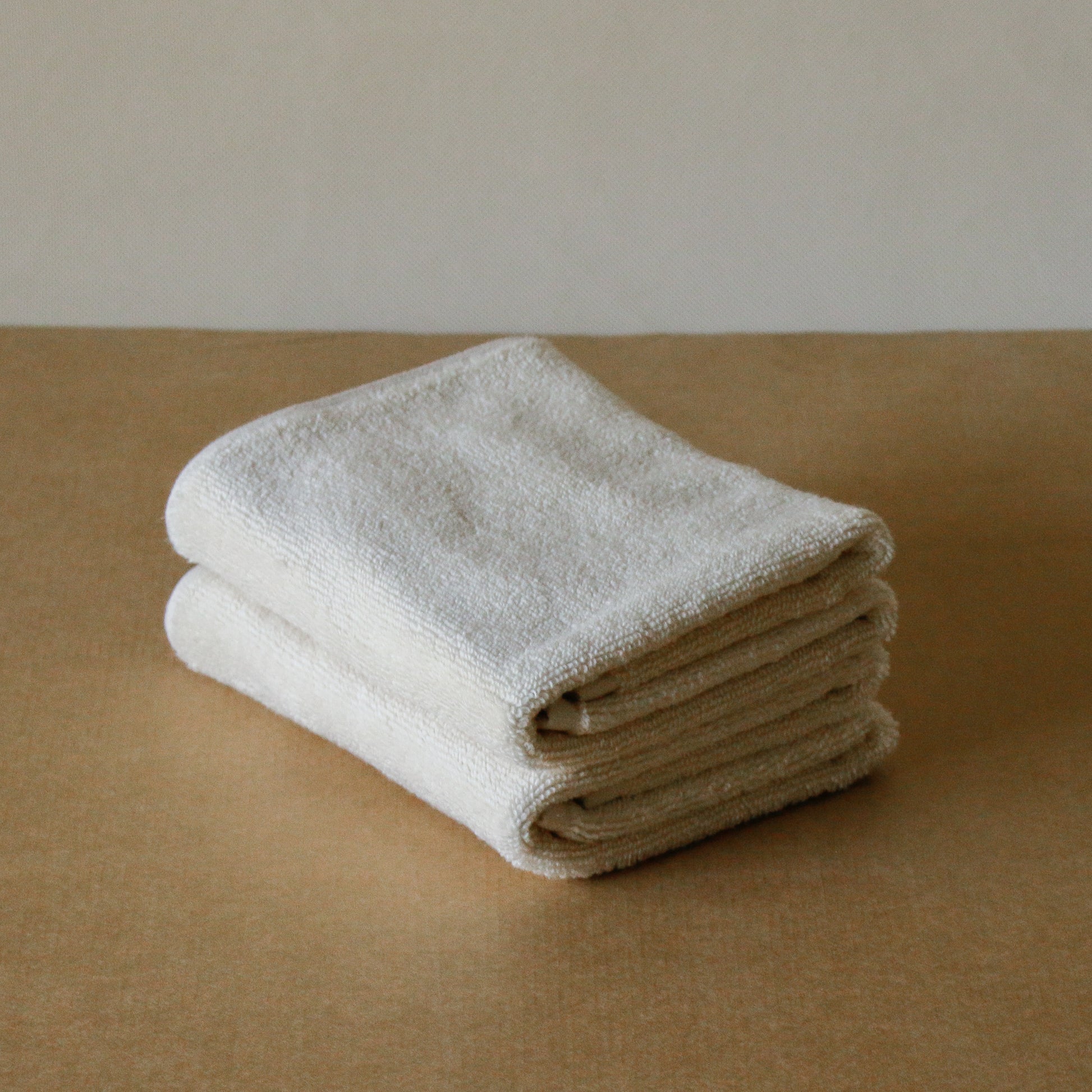 Light-colored soft terry cotton towel set with bath, hand, and face towels, plush and highly absorbent.