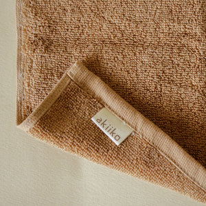 Light-colored soft terry cotton towel set with bath, hand, and face towels, plush and highly absorbent.