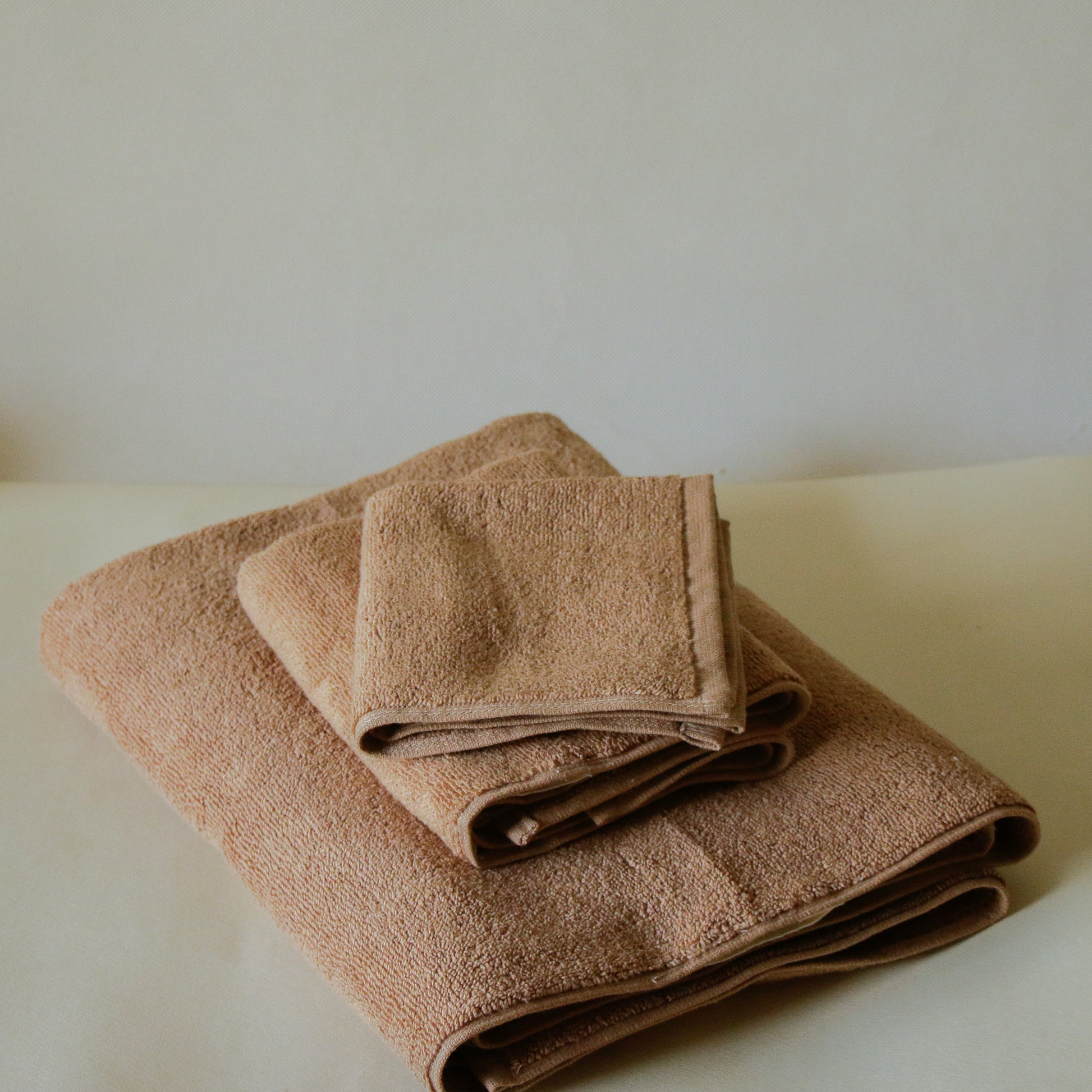 Light-colored soft terry cotton towel set with bath, hand, and face towels, plush and highly absorbent.