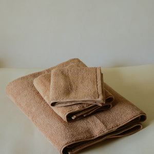 Light-colored soft terry cotton towel set with bath, hand, and face towels, plush and highly absorbent.