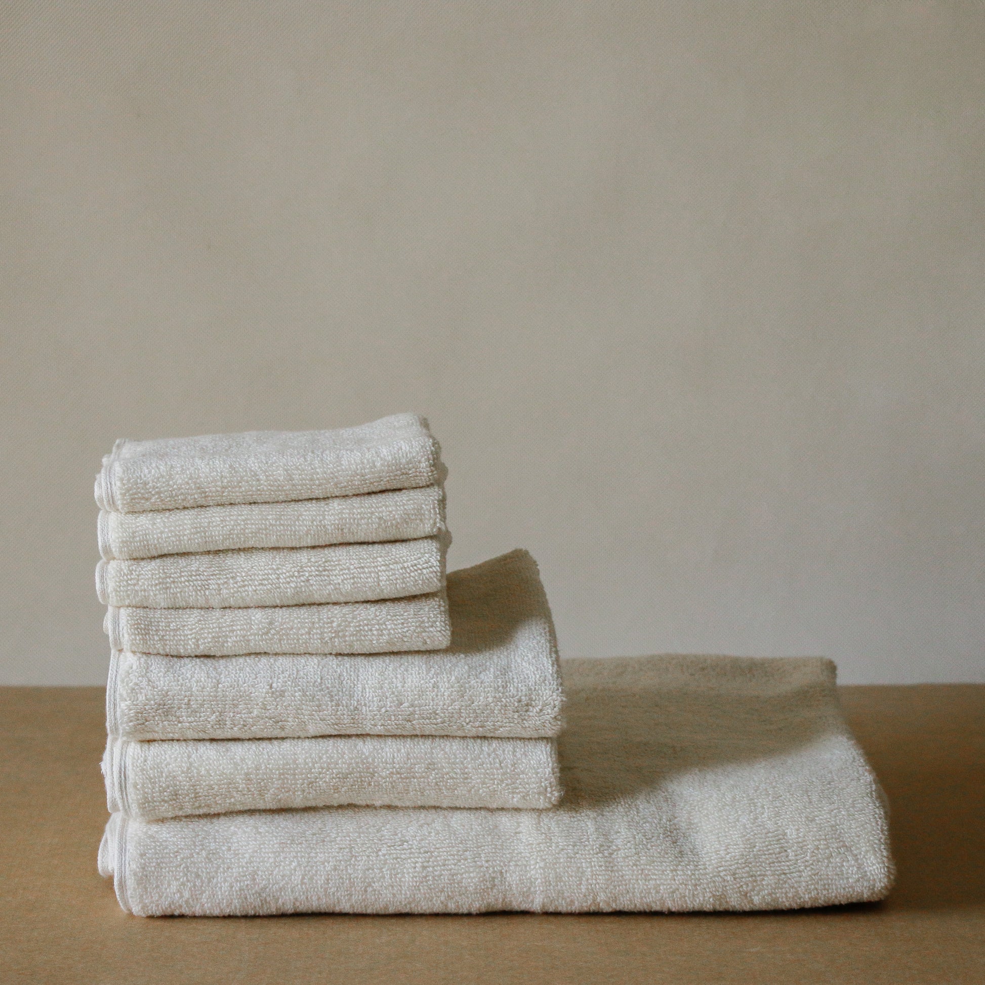 Light-colored soft terry cotton towel set with bath, hand, and face towels, plush and highly absorbent.