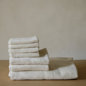 Light-colored soft terry cotton towel set with bath, hand, and face towels, plush and highly absorbent.