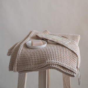 Latte-colored waffle bath towel, 135x75 cm, soft, lightweight, and absorbent, made from cotton and luffa blend.