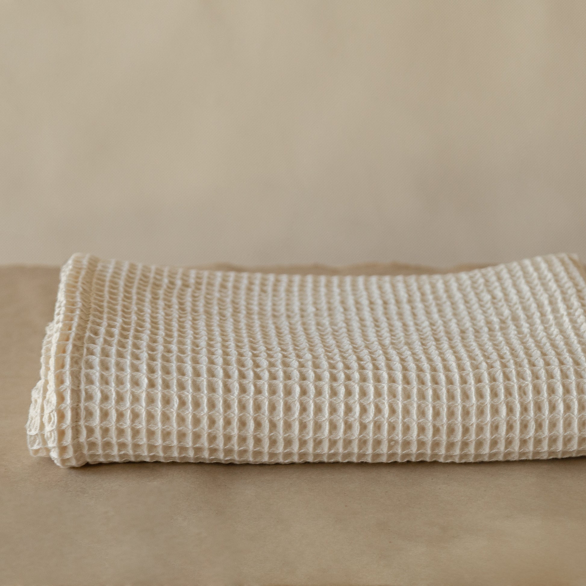 Natural-colored waffle cotton bath towel, 135x75 cm, soft, lightweight, and highly absorbent with textured weave.