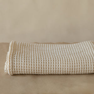 Natural-colored waffle cotton bath towel, 135x75 cm, soft, lightweight, and highly absorbent with textured weave.