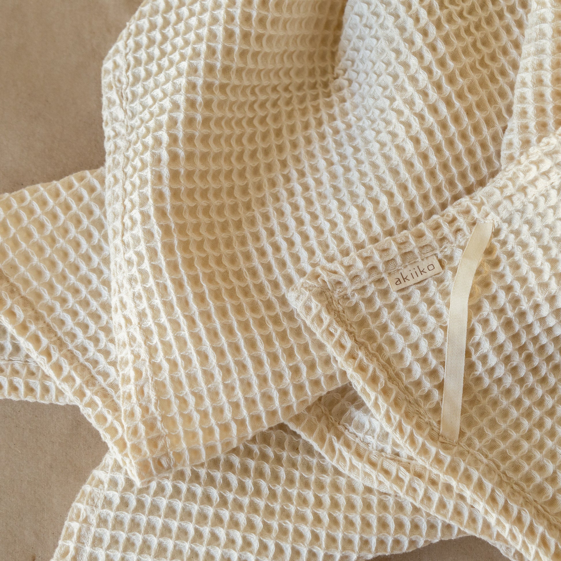 Natural-colored waffle cotton bath towel, 135x75 cm, soft, lightweight, and highly absorbent with textured weave.