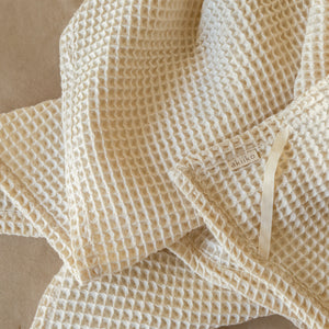 Natural-colored waffle cotton bath towel, 135x75 cm, soft, lightweight, and highly absorbent with textured weave.