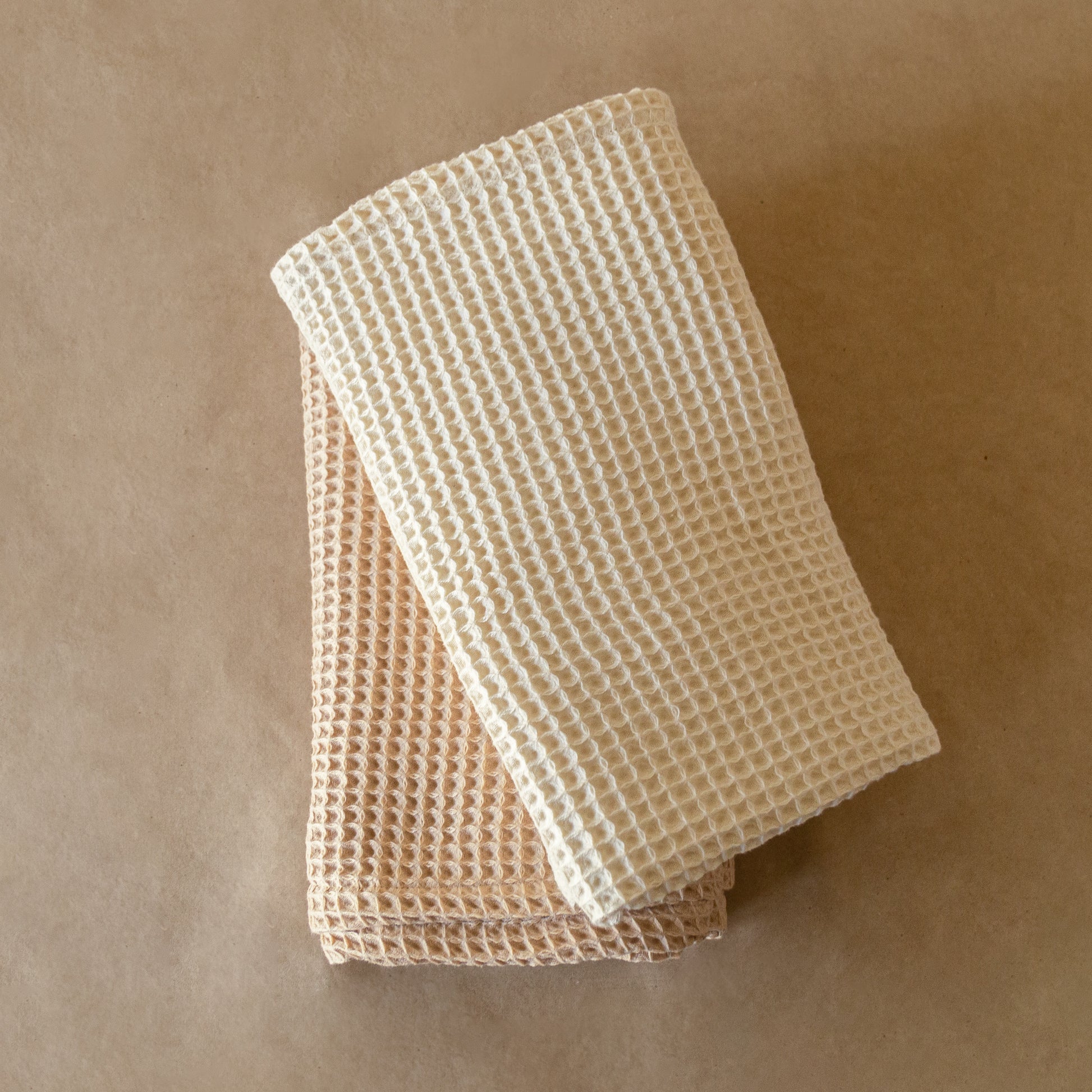 Natural-colored waffle cotton bath towel, 135x75 cm, soft, lightweight, and highly absorbent with textured weave.