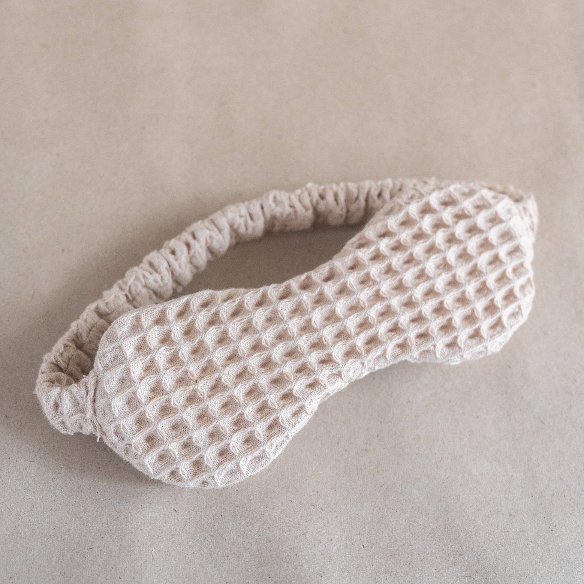 Cotton waffle sleep mask with textured pique fabric, elasticated band, and matching pouch.