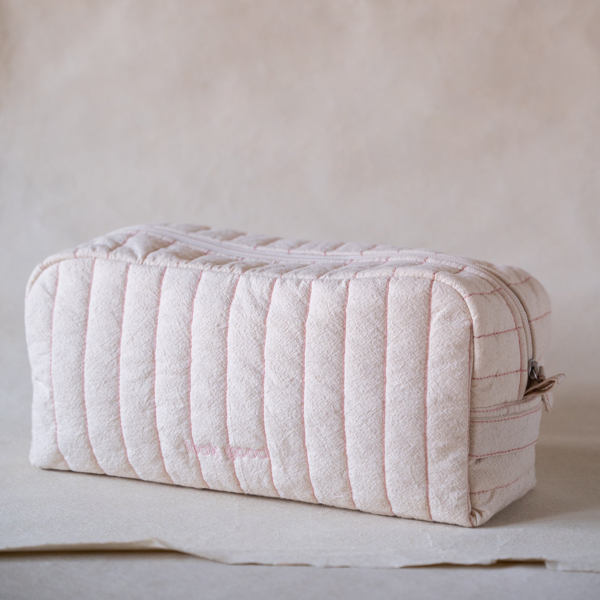 Long curved crinkle-cotton pouch with “look good” pink embroidery, front view