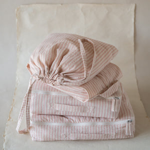 Petal-pink crinkle cotton travel set with two packing cubes, shoe bag, and laundry bag, flat lay