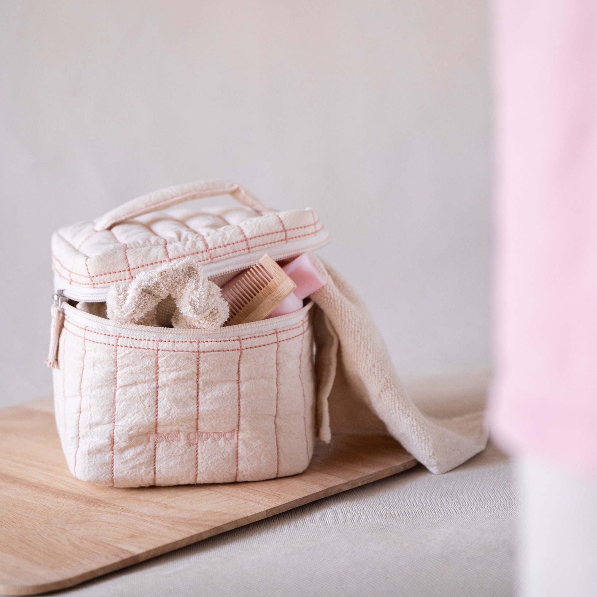 Pink-striped square vanity pouch with “feel good” embroidery, front view