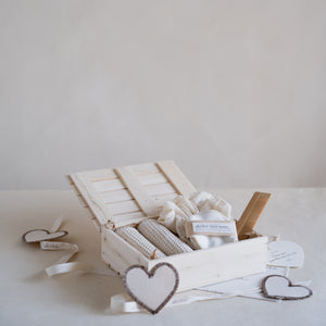Wooden gift box containing a self-care set with two waffle hand towels, Sutachi scrunchie, six reusable facial rounds, bamboo comb, and a message card.