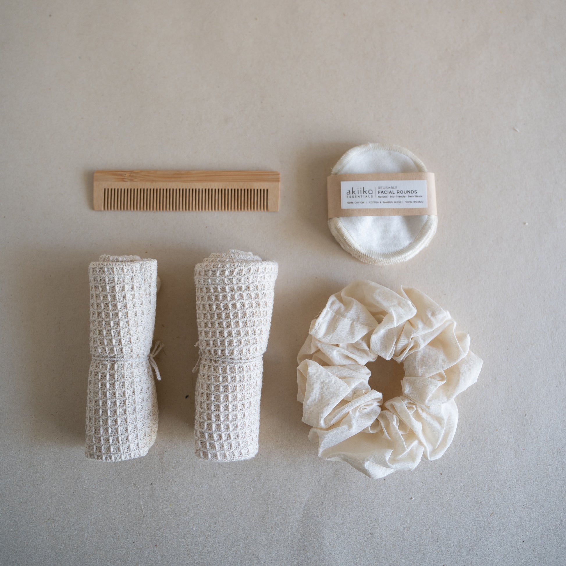 Wooden gift box containing a self-care set with two waffle hand towels, Sutachi scrunchie, six reusable facial rounds, bamboo comb, and a message card.