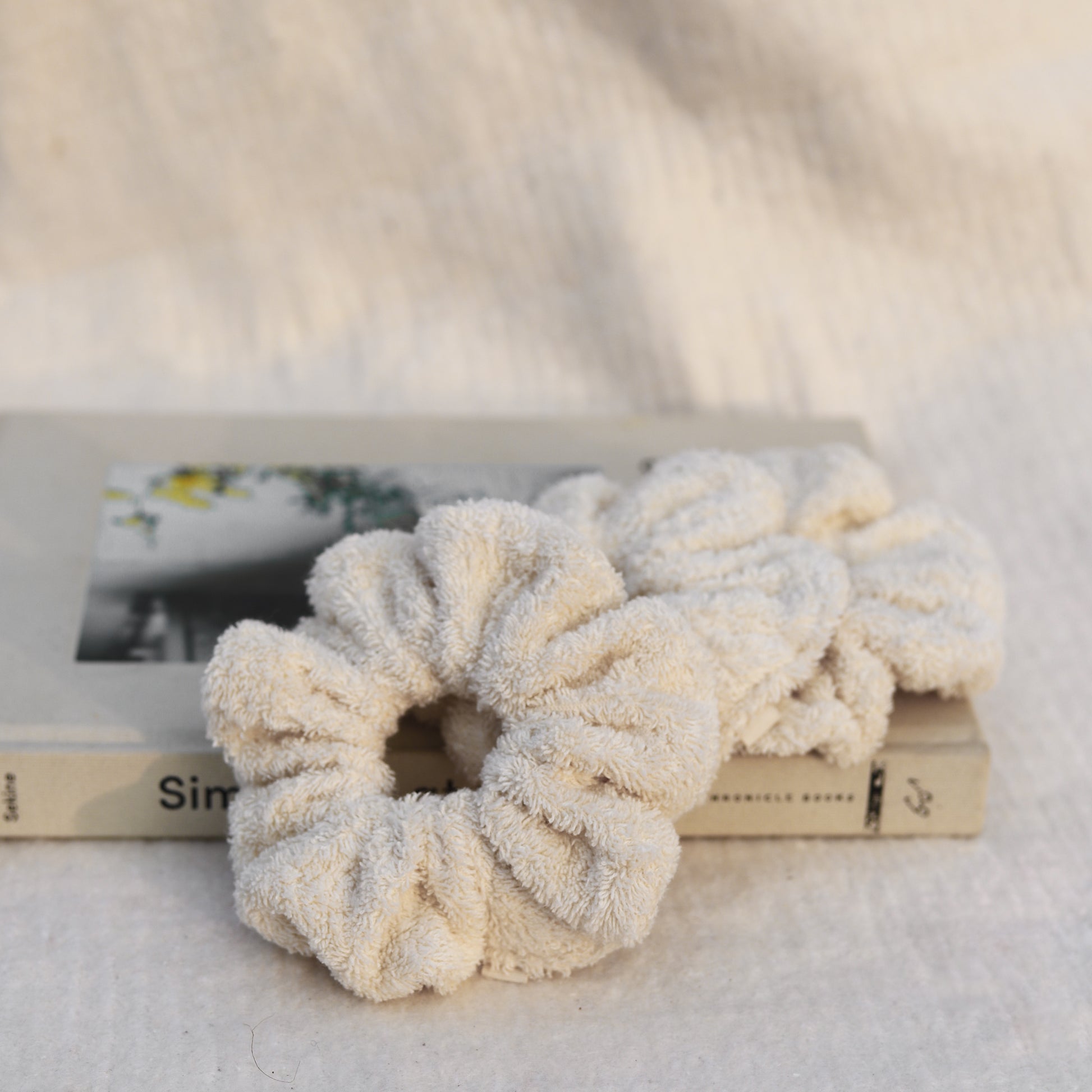 Set of three fluffy terry cotton cloud scrunchies in neutral tones, soft and lightweight, with storage bag.